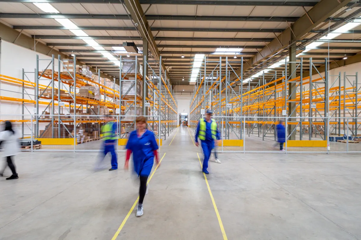 Workers using long-handled tools across a warehouse floor