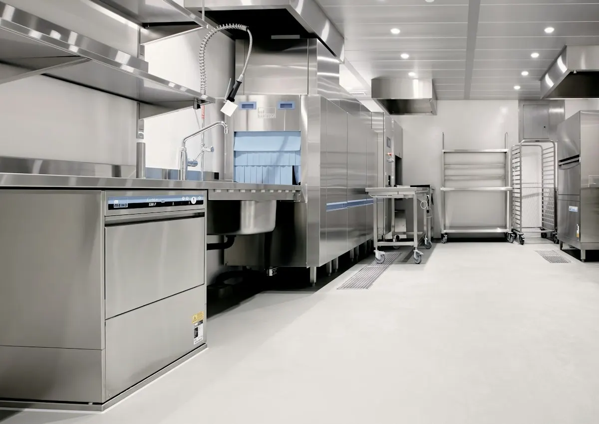 Commercial kitchen with stainless equipment and a seamless light floor